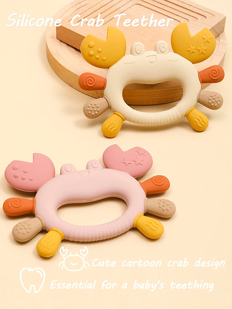 A silicone crab teether in yellow and white is shown with a cute cartoon crab design for a baby's teething.