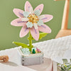 A pink and light blue rose flower building block set with green stems and white background.