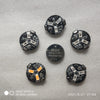 A collection of black magnetic LED diorama lights and a 3V lithium battery on a gray surface.