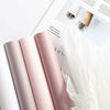 A stack of pink translucent tissue paper sheets for gift wrapping and flower bouquets is shown next to a sheet with dried flo