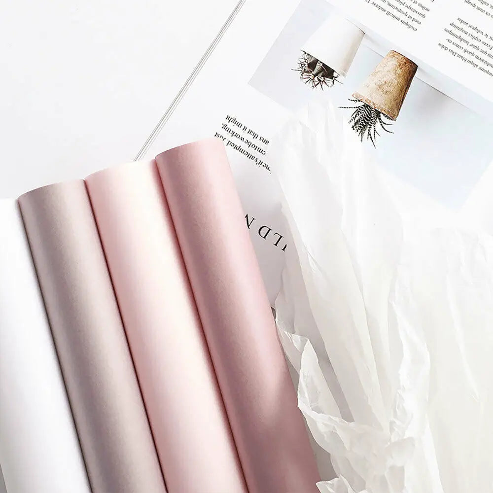 A stack of pink translucent tissue paper sheets for gift wrapping and flower bouquets is shown next to a sheet with dried flo