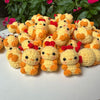 A pile of handmade crochet animal keychains in yellow and orange with red accents.