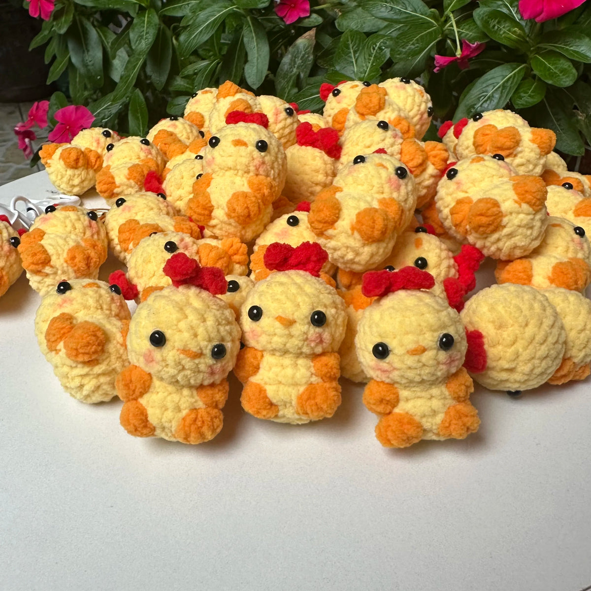 A pile of handmade crochet animal keychains in yellow and orange with red accents.