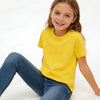 A smiling young girl wearing a bright yellow cotton t-shirt and blue jeans.