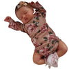 A newborn Reborn baby doll named Rosalie sleeping, wearing a floral-patterned outfit and a headband.