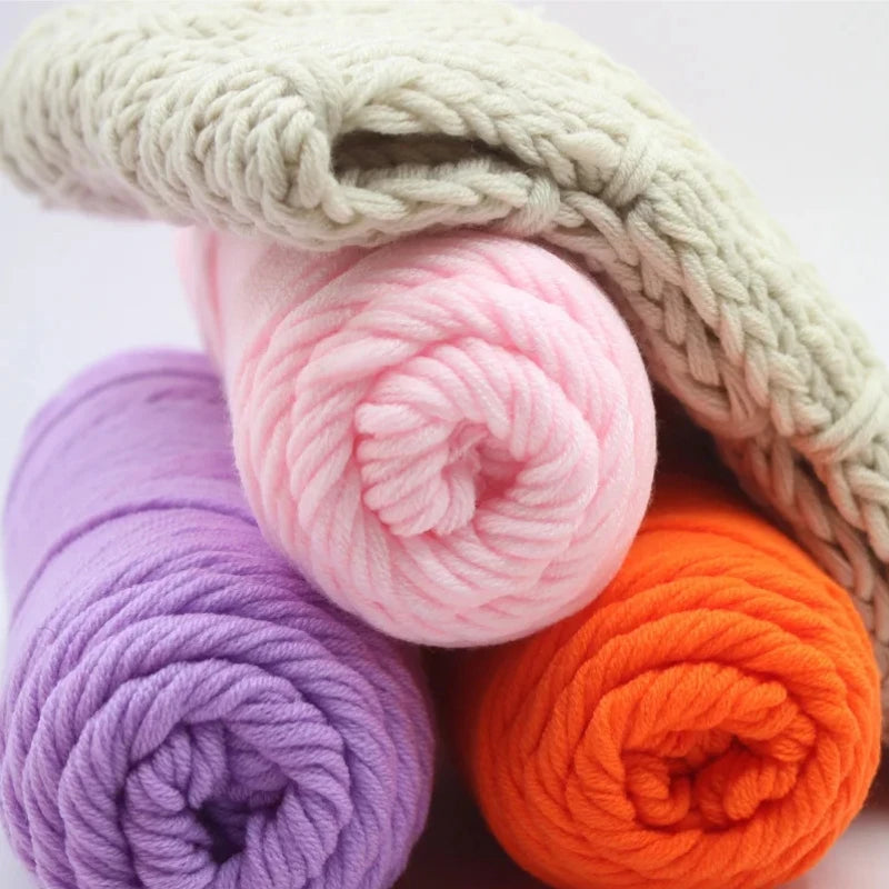 A close-up of various skeins of soft, pastel colored milk cotton yarn in purple, pink, and orange.