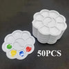 A stack of white flower-shaped disposable paint palettes with colored paint wells on a dark surface.