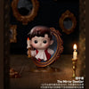 A collectible figure of a child with dark hair and rosy cheeks is displayed in an ornate mirror frame.
