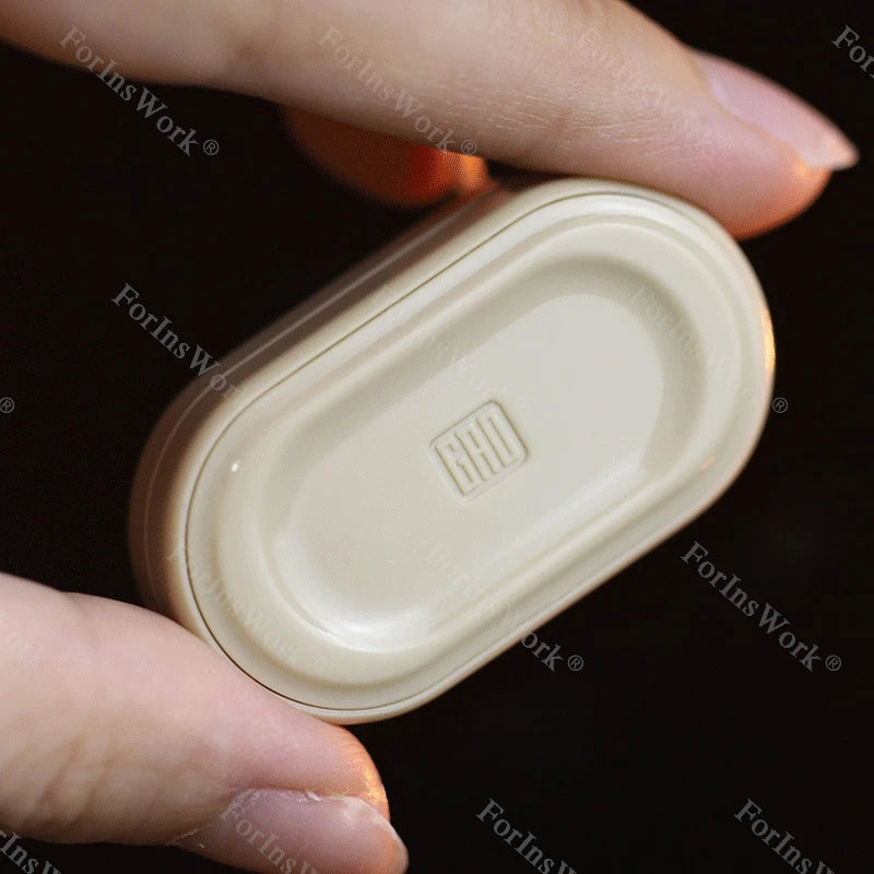 A hand holds a beige metal mechanical fidget slider with a gem design.