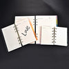 A set of four spiral-bound notebooks with leather covers and lined pages are displayed on a dark surface.
