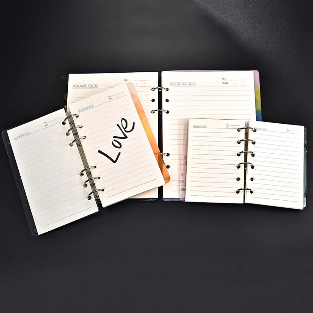 A set of four spiral-bound notebooks with leather covers and lined pages are displayed on a dark surface.