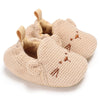 A pair of beige soft cotton baby walking shoes with anti-slip soles.