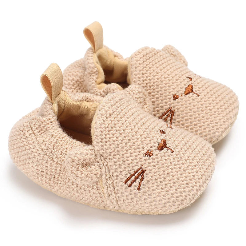 A pair of beige soft cotton baby walking shoes with anti-slip soles.