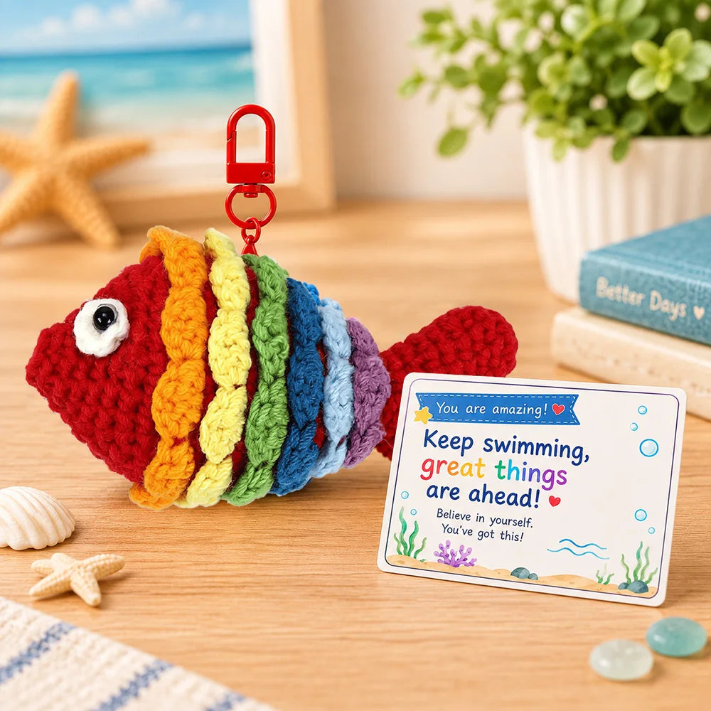 Handmade crochet fish toy with a motivational card on a wooden surface