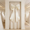 Oversized creamy white satin bow decoration hanging in a doorway