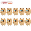 Ten small, light brown plush toys shaped like capybaras with blue tongues.