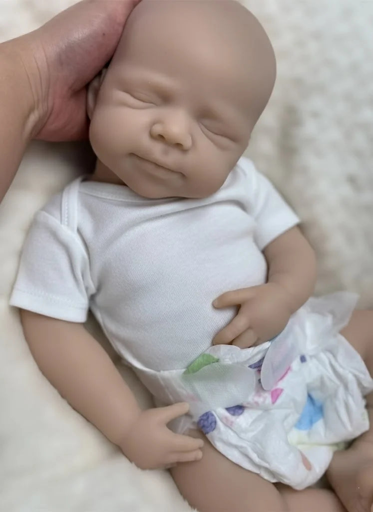 A lifelike 18-inch silicone reborn baby doll named Pascale wearing a white shirt and diaper, photographed from above.