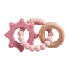 A pink silicone planet teether and a wooden ring are shown together.