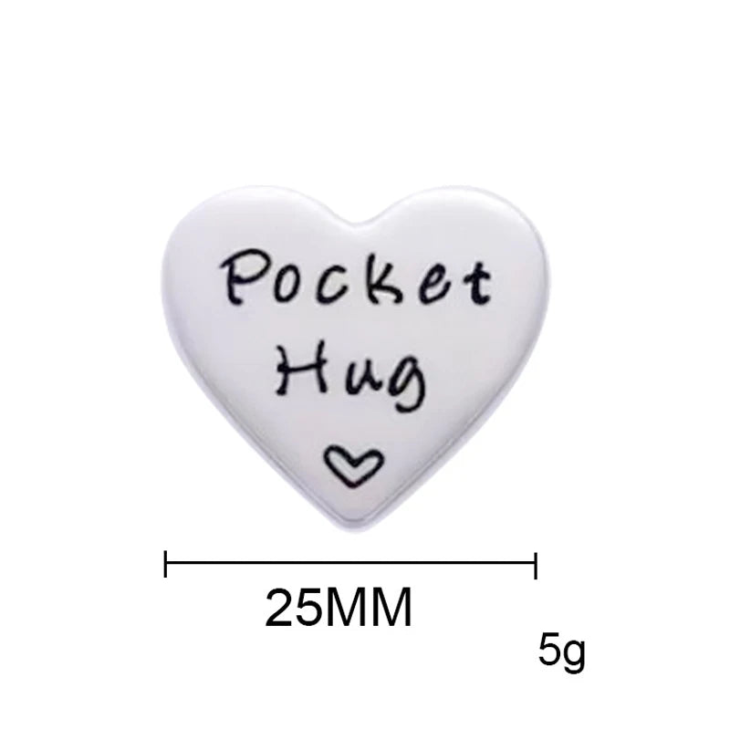 A white heart-shaped token with the words Pocket Hug engraved on it, measuring 25mm and weighing 5g.