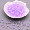 A pile of translucent purple and pink water drop glass beads in a white dish.