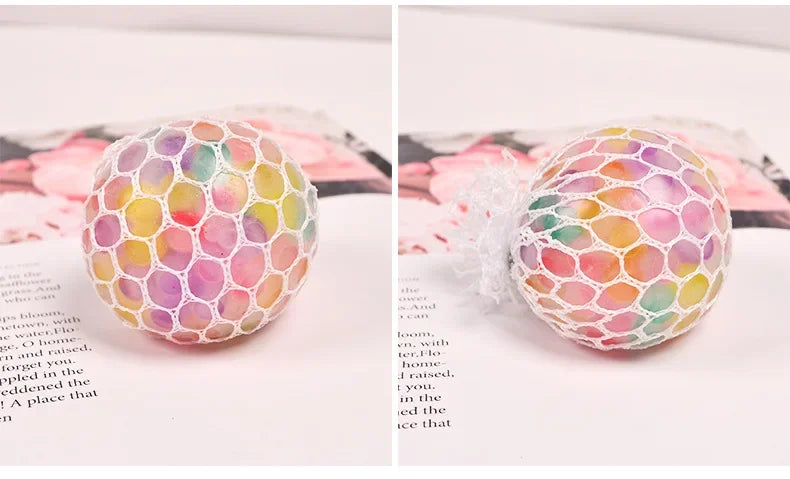 A close-up of a rainbow squishy stress relief ball with multicolored, soft, textured surface.