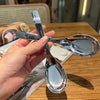 A hand holds a silver spoon and fork on a wooden table.