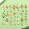 A collection of vintage gold-toned key charms and pendants for jewelry making displayed on a light green surface.