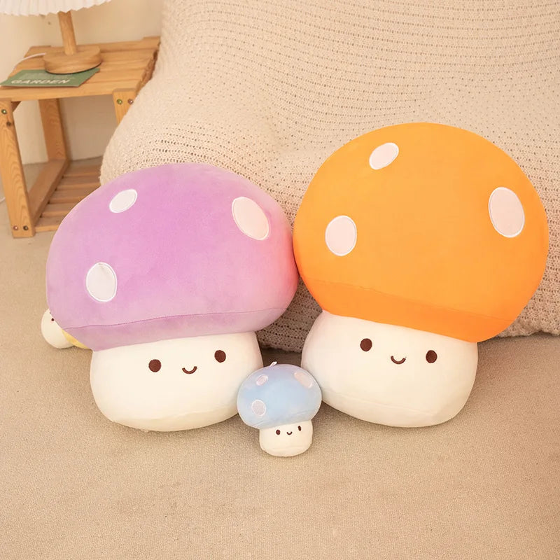 A set of soft, colorful mushroom plush pillows in purple, orange, and white resting on a beige surface.