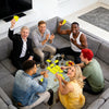 A group of friends and family are playing an interactive card game together on a couch.