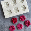 A silicone mold with multiple rose flower shapes for candle and soap making is shown on a gray surface.