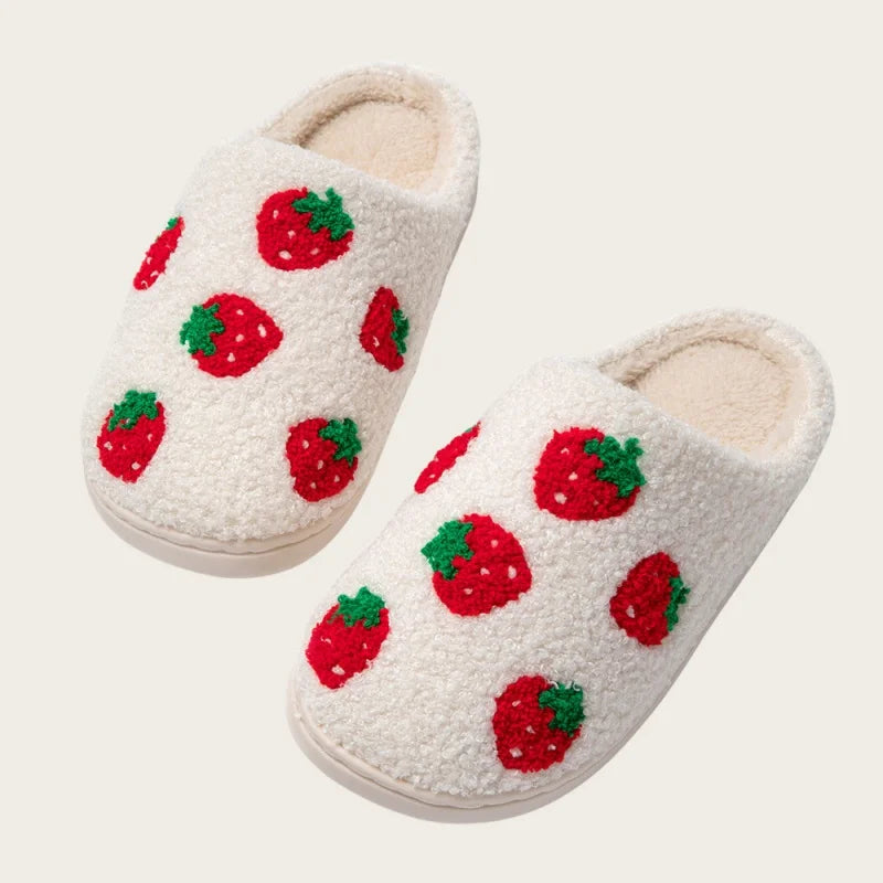 A pair of cream-colored plush indoor slippers decorated with red strawberry patterns.