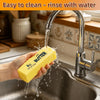 A hand is rinsing a yellow butter-shaped squeeze stress relief food item under running water in a kitchen sink.