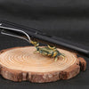 A brass crab figurine is placed on a wooden slice next to a black desk tool.
