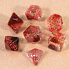 A collection of translucent red and pink glitter polyhedral dice including D4, D6, D8, D10, D12, and D20 scattered on a light