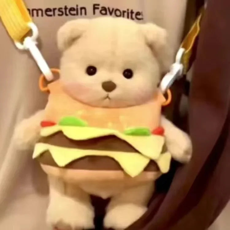 A fluffy white teddy bear plush wearing a yellow and green hamburger-themed dress.