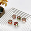 Collection de billes en verre faites à la main de différentes couleurs, y compris vert, rouge et blanc, posées sur un plateau