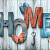 Wooden letters spelling HOME decorated with floral elements and a key on a light wood background