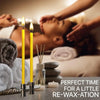 A set of natural beeswax taper candles in yellow and white are shown on a table with spa elements.