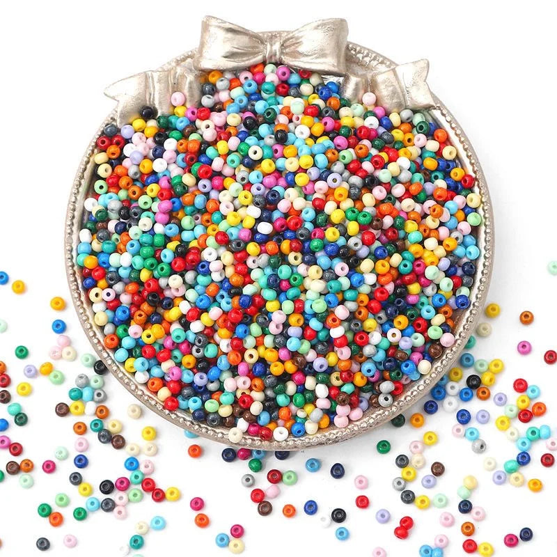A circular display of 100 rainbow pony beads in various colors scattered on a white surface.