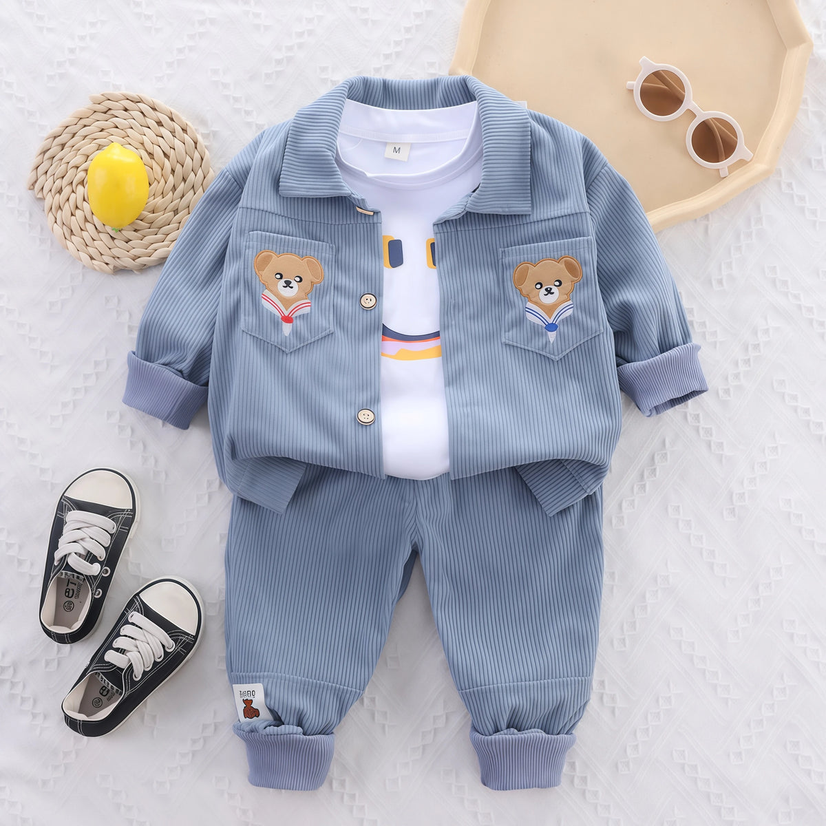 A light blue corduroy tracksuit set for a child featuring a jacket and matching pants with bear embroidery.