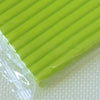 A close-up view of a bright green, ridged polymer clay block resting on a white surface.