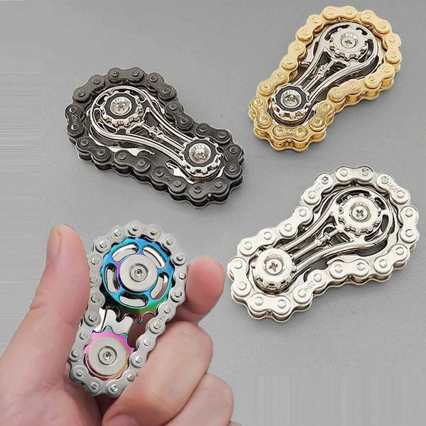 A hand holds several metal fidget spinners of different finishes, including silver, black, and gold.
