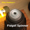 A black fidget spinner is shown on a wooden surface next to a bright light source, demonstrating Play Method 1.
