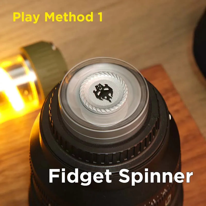 A black fidget spinner is shown on a wooden surface next to a bright light source, demonstrating Play Method 1.
