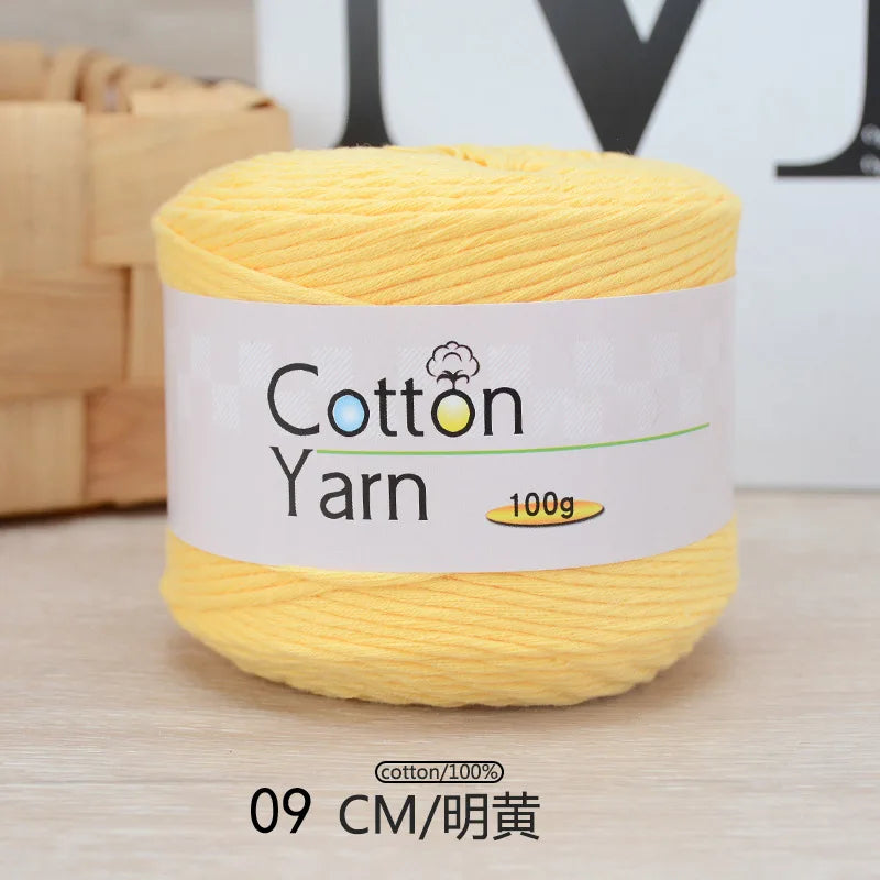 A spool of yellow cotton yarn labeled as 100% Cotton Yarn, measuring 9 cm.
