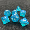 A set of seven iridescent blue acrylic polyhedral dice resting on a dark gray surface.