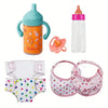 A set of baby feeding and care accessories including a bottle, a silicone toy, and pink fabric items for a baby.