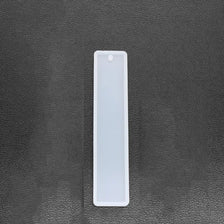 A white flexible silicone mold for resin bookmarks is shown against a dark gray surface.