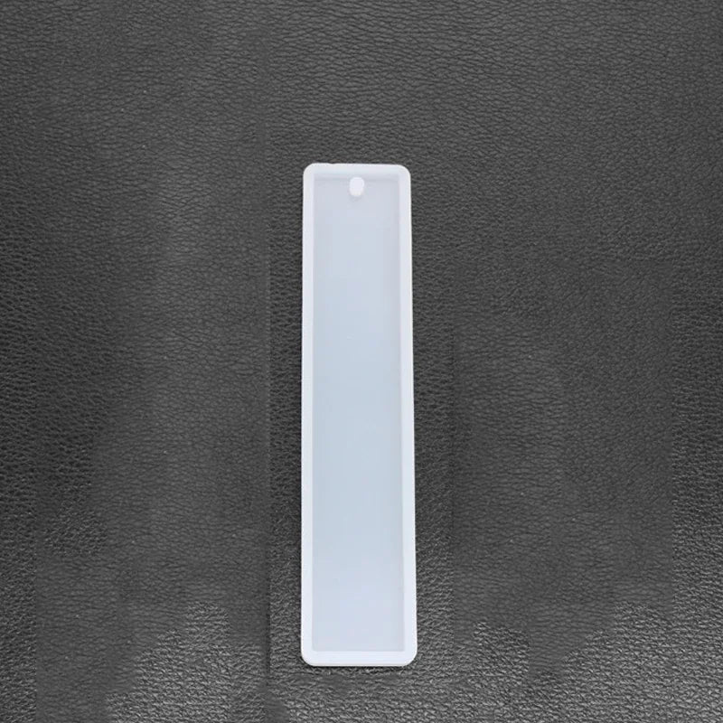 A white flexible silicone mold for resin bookmarks is shown against a dark gray surface.