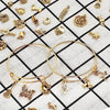 A collection of silver-tone jewelry making components including bangles, charms, and tools displayed on a black and white che